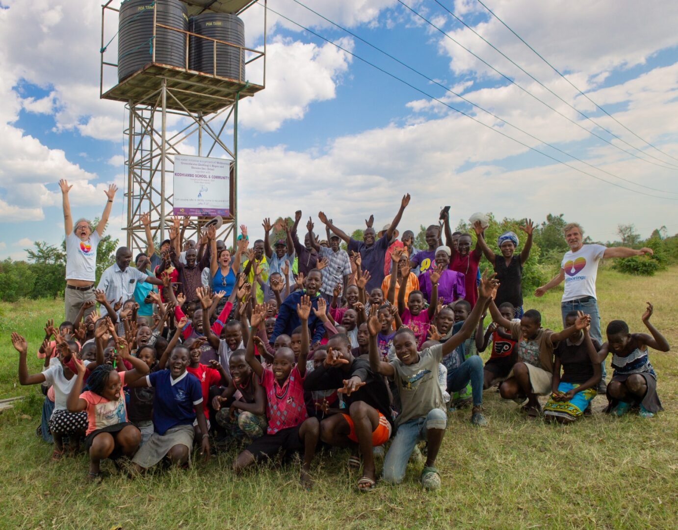 Jubelnde Kinder und Dorfbewohner und das WellBoring-Team vor einem Solarbrunnen in Afrika – ein Symbol für die Kraft von Brunnenbau Spenden in Afrika. Dank großzügiger Unterstützung konnte dieser Brunnen gebaut werden und versorgt nun eine ganze Gemeinde mit sauberem Trinkwasser. Spende für den Brunnenbau in Afrika und schenke Zukunft!