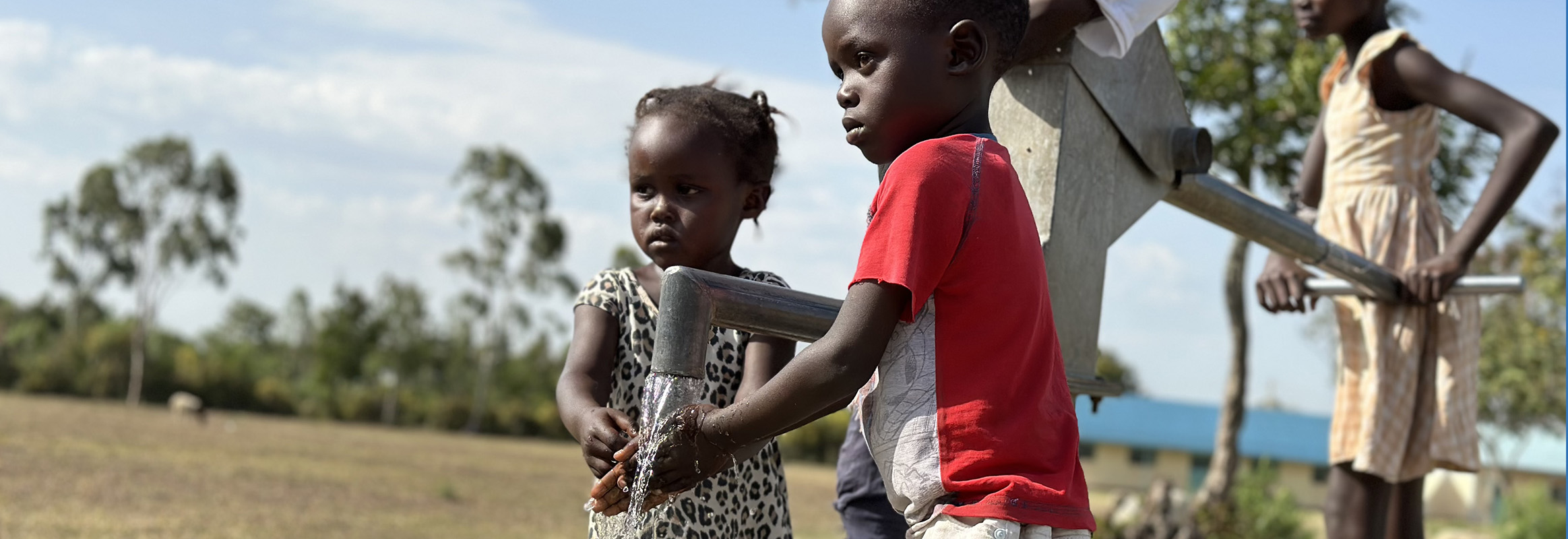 Children accessing a manual water pump in rural Africa, highlighting the need for well-boring services to secure clean drinking water