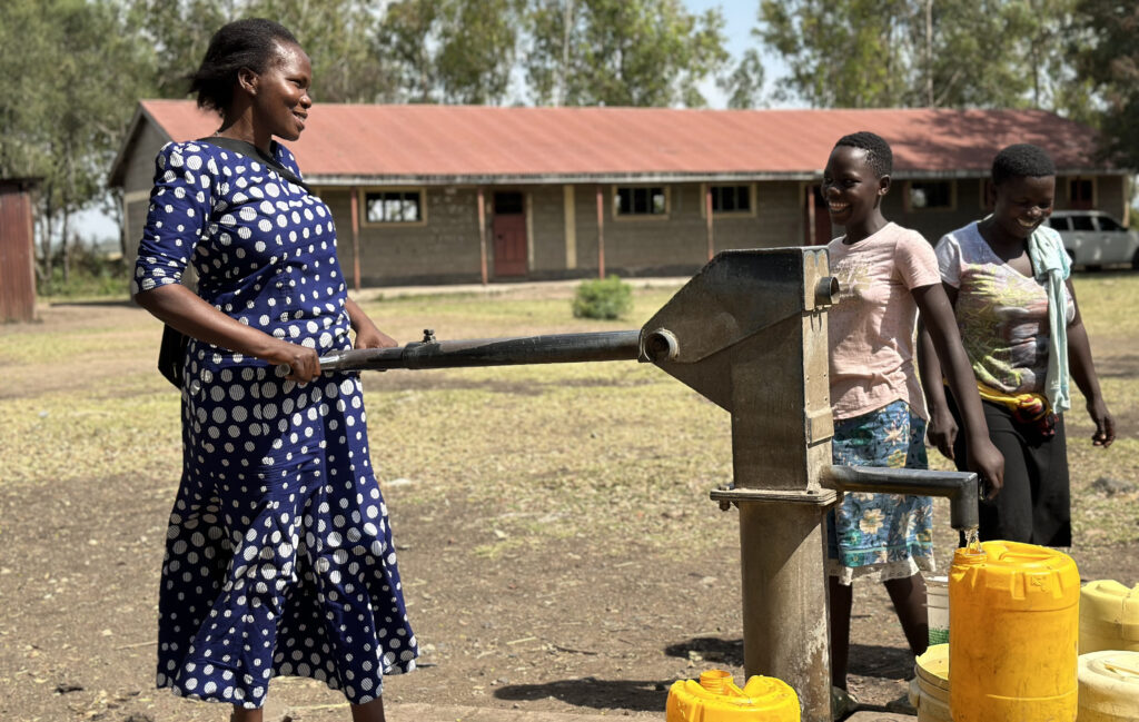 Community members fetching clean water from a WellBoring well in a Kenyan primary school yard, fulfilling a shared resource promise.