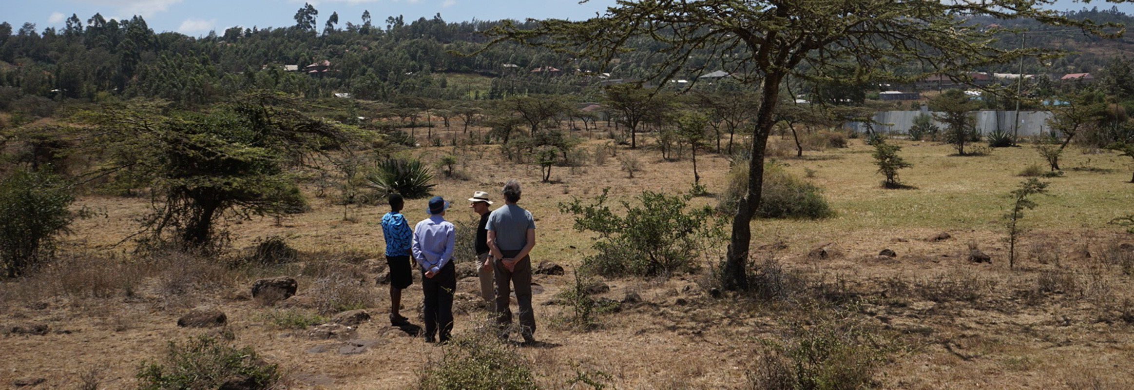Three individuals standing in a dry, open landscape, observing the terrain for the potential installation of a new water well, illustrating WellBoring's hands-on approach to providing sustainable water solutions in rural regions.