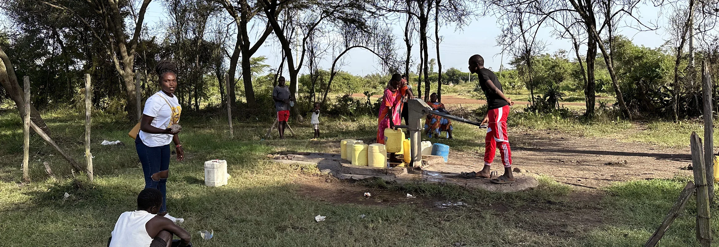 Local residents gather around a WellBoring hand-pump well in a rural African setting, drawing clean water for their daily needs.
